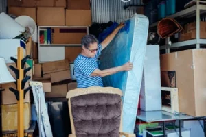 Umzugstipps - Ein Mann steht inmitten von sehr vielen Umzugsboxen und Möbel.