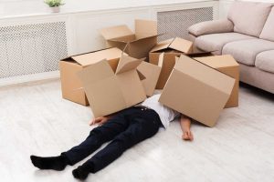 Man ligt onder een aantal kartonnen dozen